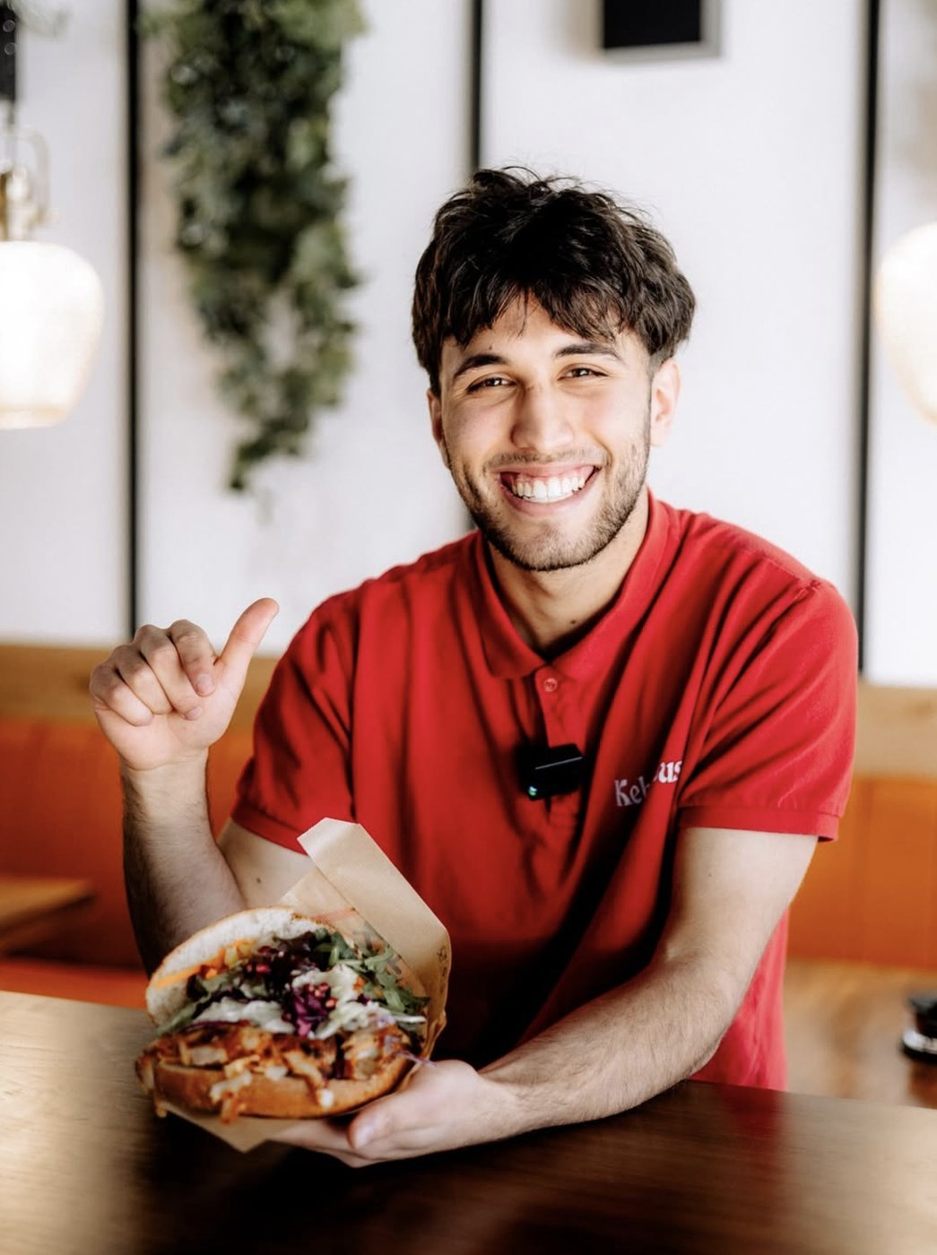 Lächelnder Mitarbeiter mit frisch zubereitetem Sandwich
